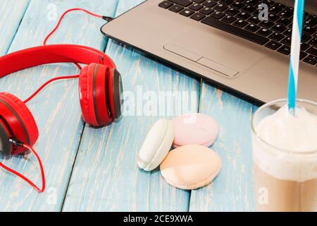 Offener Laptop mit weißer Tasse Kaffee, Marshmallows und roten Kopfhörern. Stockfoto