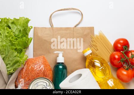 Lieferservice. Kaufen Sie Produkte online während der Quarantäne. Gesunde Ernährung und Antiseptikum mit Papiertüte auf weißem Hintergrund. Salat, Sonnenblumenöl Stockfoto