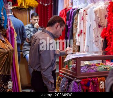 Damaskus, Syrien 03/28/2010: Ein Ladenbesitzer in Al Hamidiyah Souq liest Zeitung, während er am Eingang seiner Boutique steht. Er hat traditionelle Stockfoto