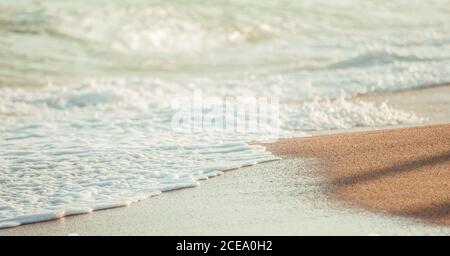 Blick auf weiße, weiche Welle mit Schaum am glatten Sandstrand im Sonnenlicht, Barcelona Stockfoto