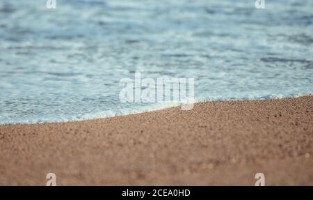 Blick auf weiße, weiche Welle mit Schaum am glatten Sandstrand im Sonnenlicht, Barcelona Stockfoto