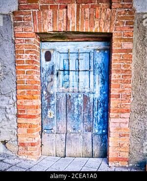Alte blaue Holztür mit schönem Ziegelrahmen Stockfoto