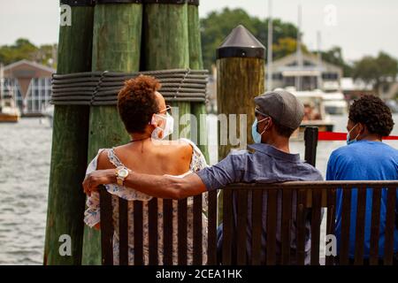 Annapolis, MD 08/21/2020: Eine afroamerikanische Familie sitzt auf einer Bank in Annapolis Marina und schaut auf vorbeifahrende Boote. Der Mann legt seinen Arm über Stockfoto