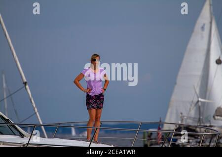 Annapolis, MD 08/21/2020: Eine blonde, attraktive Frau in den Vierzigern mit Fliederbluse und Rock steht an Deck einer Yacht mit den Händen Stockfoto