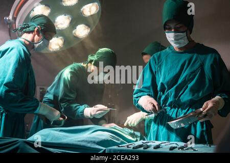Operationssaal Krankenschwester bereiten chirurgische Geräte für Chirurgen Arzt mit Medical Team Durchführung chirurgische Operation im Operationssaal ODER. Medizinische Gesundheit Stockfoto