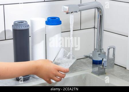 Der Wasserhahn, aus dem das Wasser fließt. Durst löschen. Wasserprobleme in einigen Ländern.das Glas ist mit Wasser gefüllt. Stockfoto