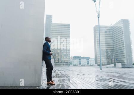 Afroamerikanischer Geschäftsmann, der sich im Freien an einer Wand lehnt Stockfoto