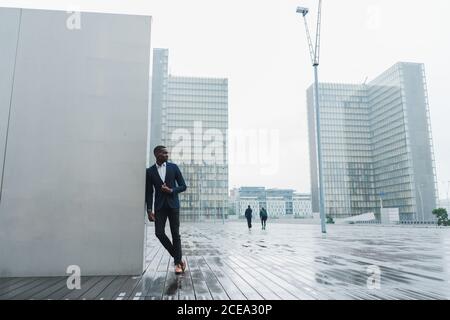 Afroamerikanischer Geschäftsmann, der sich im Freien an einer Wand lehnt Stockfoto