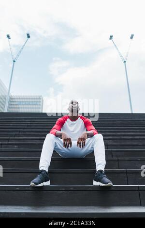 Ethnischer Mann, der nach dem Training auf der Treppe ruht Stockfoto