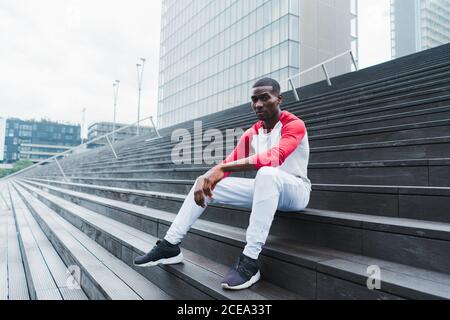 Ethnischer Mann, der nach dem Training auf der Treppe ruht Stockfoto