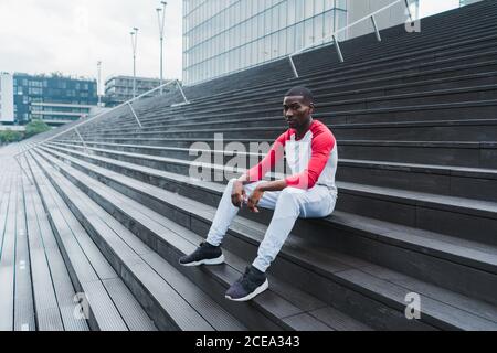 Ethnischer Mann, der nach dem Training auf der Treppe ruht Stockfoto