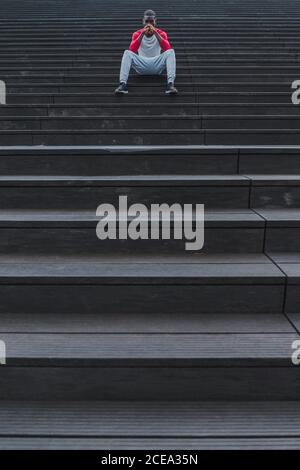 Ethnischer Mann, der nach dem Training auf der Treppe ruht Stockfoto