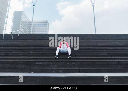 Ethnischer Mann, der nach dem Training auf der Treppe ruht Stockfoto