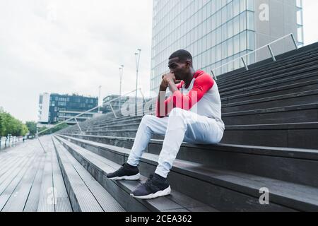 Ethnischer Mann, der nach dem Training auf der Treppe ruht Stockfoto