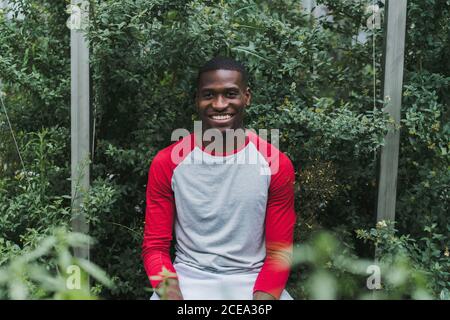 Schöner afroamerikanischer Mann, der an Büschen steht Stockfoto