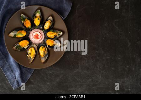 Köstliche Muscheln mit Gemüsescheiben und Granatapfelkernen liegen Auf Platte neben Stoffstück auf grauem Hintergrund Stockfoto