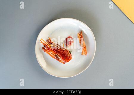 Schale von leckeren gekochten Garnelen liegen auf Keramikplatte auf Blauer Hintergrund Stockfoto