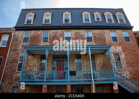 Ein heruntergekommenes großes Vintage-Haus mit verfärbter Ziegelfassade im historischen Viertel Annapolis, Maryland. Das Gebäude hat blaue Holzpo Stockfoto