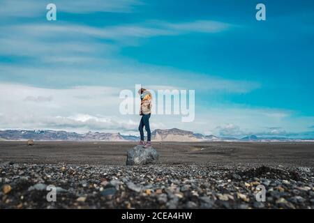 Seitenansicht einer jungen Frau, die in einer atemberaubenden Landschaft steht und die Aussicht genießt, während sie durch Island reist Stockfoto