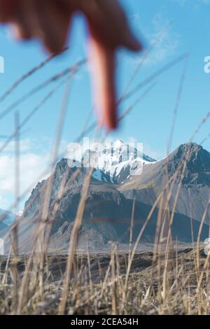 Verschwommene Hand zeigt mit dem Finger auf schneebedeckten Gipfel in genial landschaft islands Stockfoto