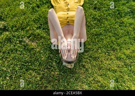 Woman lying on grass with hands on face Stockfoto