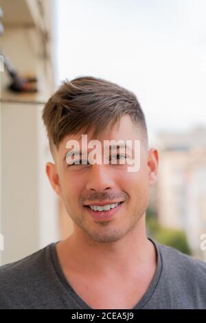 Hübscher junger Mann in grauem T-Shirt, der die Kamera im Stehen betrachtet Im Freien Stockfoto