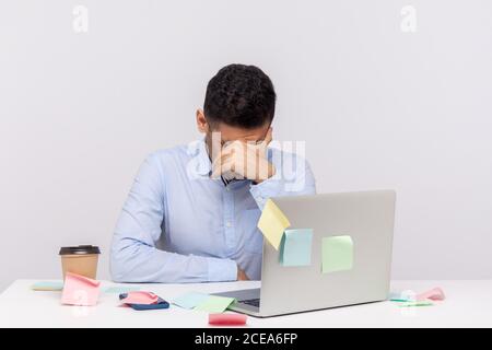 Müde unglücklicher Mann Mitarbeiter sitzen im Büro Arbeitsplatz mit Haftnotizen überall, verbeugen Kopf weinen, versteckt Gesicht Gefühl depressiv frustriert, ups Stockfoto