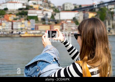 Frau, die von der Brücke aus einen Fluss auf dem Smartphone fotografiert Stockfoto