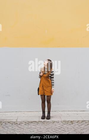 Junge lächelnde Frau in der Nähe der grauen Wand Stockfoto