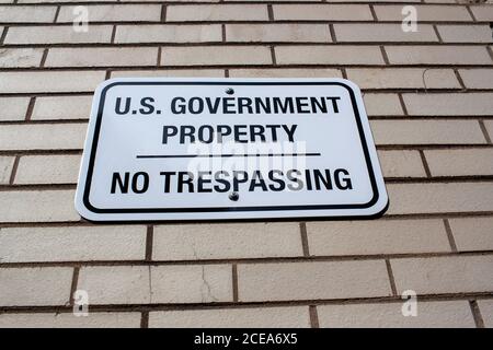 Annapolis, MD 08/21/2020: Eine weiße Metallplatte, die an einer Ziegelmauer befestigt ist, die ein Regierungsgebäude in Annapolis umgibt. Auf dem Schild steht: 'US-Regierung Stockfoto