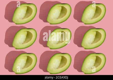 Trending Stil Muster der Hälfte seedless grün Avocado auf rosa Hintergrund mit hartem Licht. Kreative Lebensmitteltextur Stockfoto