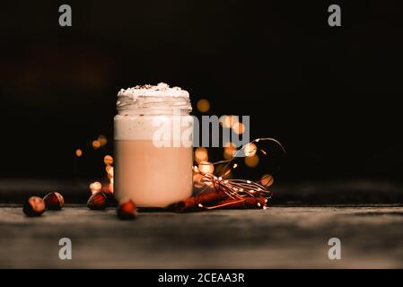 Aromatische Zimtstangen in der Nähe von Glas leckeren Kaffee mit Sahne auf Bauholz Tischplatte Stockfoto