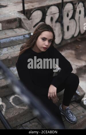 Charmante Frau in Pullover und Leggins sitzen auf der Treppe Stockfoto