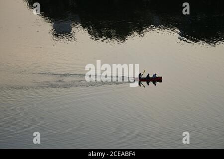 Austin, TX 18. August 2020: Drei Personen im Kanu genießen den Sonnenuntergang am Lady Bird Lake in der Innenstadt von Austin am Ende eines heißen Sommertages. Stockfoto