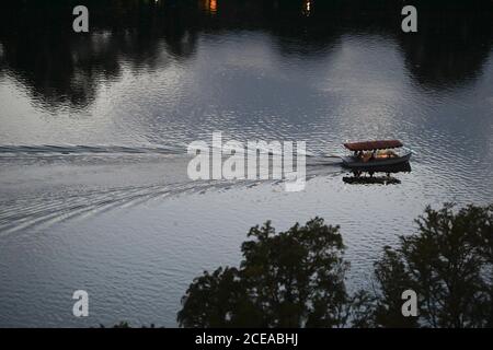 Austin, Texas, USA, 18. August 2020: Bootsfahrer in einem kleinen Elektromotorschiff genießen den Sonnenuntergang nach einem heißen Sommertag am Lady Bird Lake in der Innenstadt von Austin. ©Bob Daemmrich Stockfoto