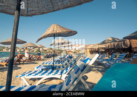 Sandstrand in Çeşme mit Strohschirmen und Liegestühlen als sehr schöner Hintergrund. Stockfoto