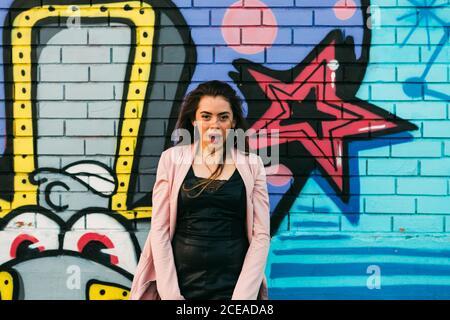 Junge lächelnde Frau in legerer Kleidung in der Nähe der Graffiti-Wand Stockfoto