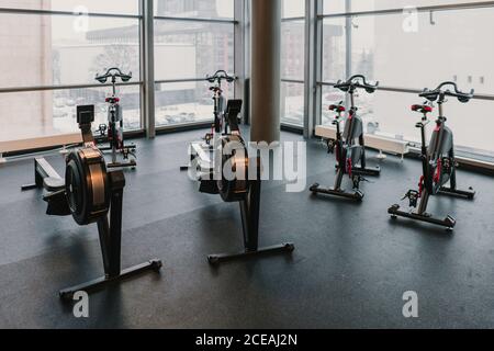 Fitnessgeräte in der Nähe von riesigen Fenstern im Fitnessraum Stockfoto