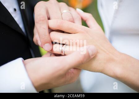 Hände des anonymen Bräutigams, der Ring auf den Finger des Unkennbaren setzt Braut während der Trauung Stockfoto