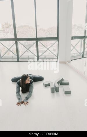 Junge, schlanke, sportliche Frau, die im Studio des hellen Zimmers ein Bein spaltet Stockfoto