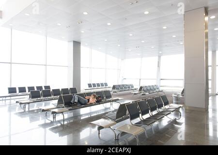 Touristenfrau liegt und ruht auf der Bank im Terminal in Thailand. Stockfoto