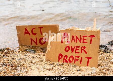 Aussterben Rebellion Protest über den Anstieg des Meeresspiegels aufgrund des Klimawandels platziert Zeichen durch die einströmende Flut. Handeln Sie jetzt, Planet über Profit-Plakate Stockfoto