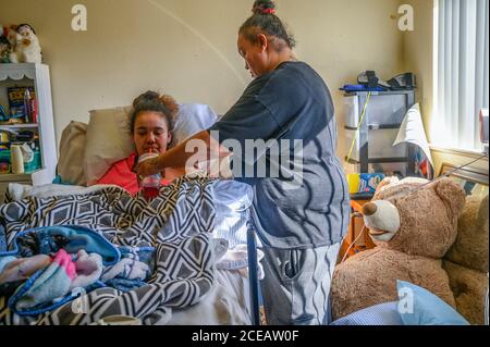 Sacramento, Kalifornien, USA. Februar 2019. Felicia Clark, 36, gibt ihrer Tochter Felicia Brent-Velasquez, 18, am Freitag, 14. Februar 2020, in Sacramento einen Drink Soda. Sie sagte, dass die Ärzte sagten, sie würde nie essen oder trinken oder nicht mit Sauerstoff versorgt werden, aber seit ihrer Rückkehr nach Hause hat sie all diesen Widrigkeiten trotzt. Brent-Velasquez sagte, sie sei stolz, dass sie ihren Katheter entfernen konnte und dass sie unter der Obhut ihrer Mutter keine Wundstellen mehr habe. Quelle: Renée C. Byer/ZUMA Wire/Alamy Live News Stockfoto