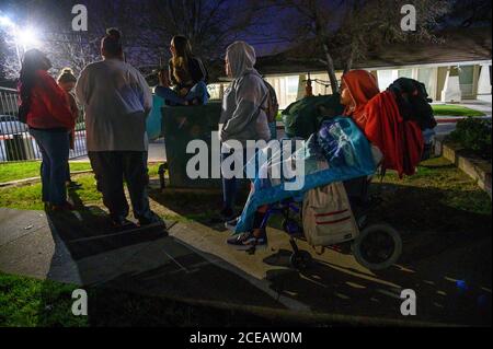 Sacramento, Kalifornien, USA. Februar 2020. Felicia Brent-Velasquez, rechts, ist in Decken gebündelt, als ihre beiden Schwestern Paulina, Mitte, und Angelique, sitzen auf einem Container, ihre Mutter Felicia Clark, zurück zur Kamera, vor dem Kinderheim von Sacramento für die wöchentliche Protest ihrer Mutter am Freitag, 14. Februar 2020. Angelique ist ein Bewohner des Hauses und war aus dem AWOL gegangen und wurde von zwei Mitarbeitern auf der linken Seite beschattet. Quelle: Renée C. Byer/ZUMA Wire/Alamy Live News Stockfoto