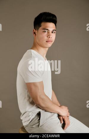 Junger Mann sitzt auf einem Stuhl im Studio Stockfoto