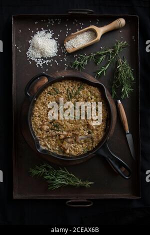 Von oben Risotto mit Gewürzen und Rosmarin auf einer Pfanne. Stockfoto