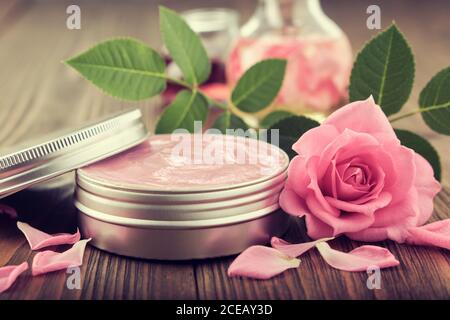 Glas mit einer hausgemachten feuchtigkeitsspendenden Beauty-Creme und rosa Rosenblüte. Herstellung von kosmetischen Produkten zu Hause. Stockfoto