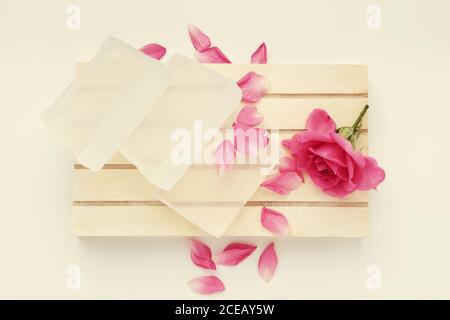 Seifenstück und Rosenblume. Basis für die Herstellung von Seife und rosa Rose Knospe auf Holzpalette. Draufsicht. Stockfoto