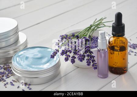 Natürliche Lavendelcreme, Lavendelblüten, Tropfflasche mit ätherischem Lavendelöl und parfümiertes Wasser oder Hydrolat in einer Sprühflasche. Stockfoto