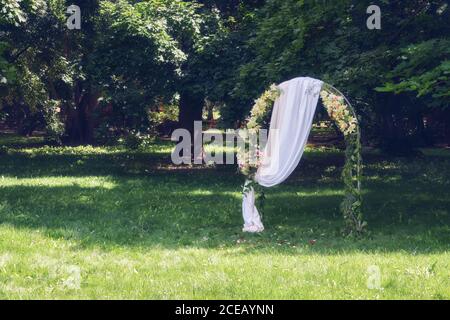 Wunderschön dekorierter romantischer Ort - Hochzeitsbogen für Hochzeitszeremonie im Sommerpark im Freien. Stockfoto